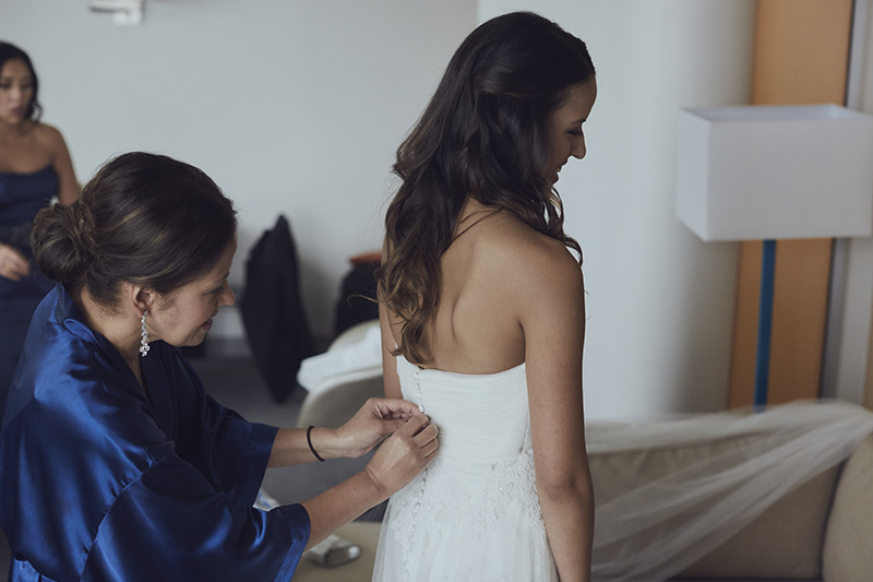 mother helping bride put dress on