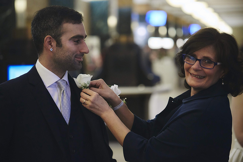 mother of the groom putting boutonniere on groom