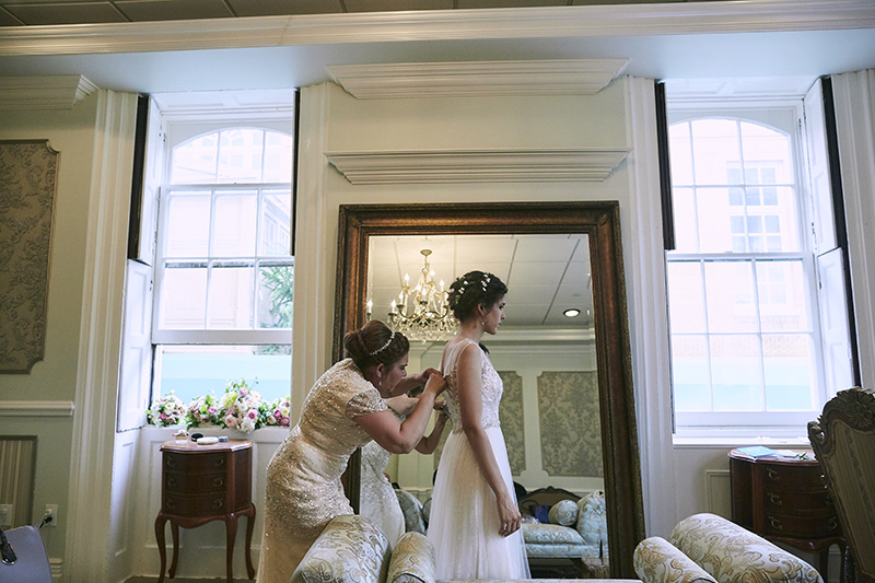 mother helping bride get into dress