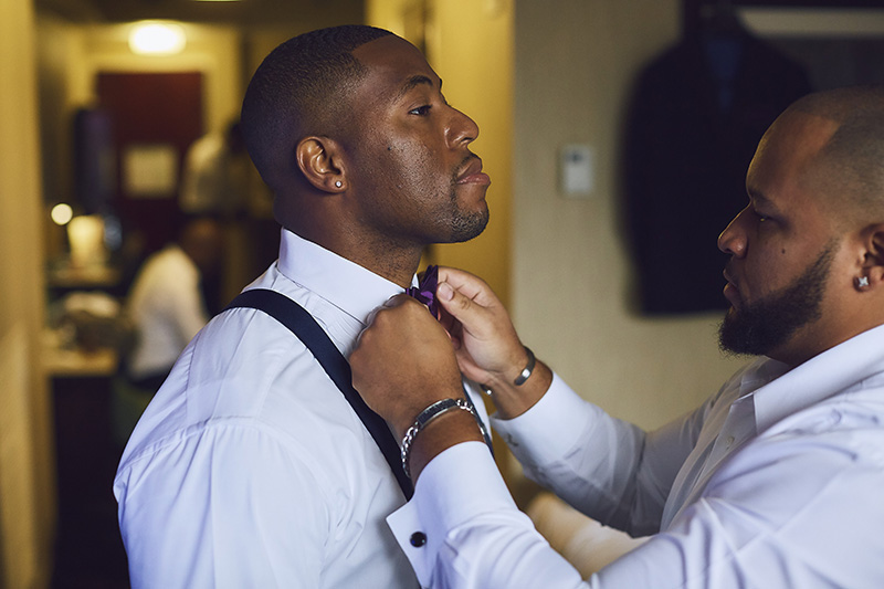 groom putting a bow tie on