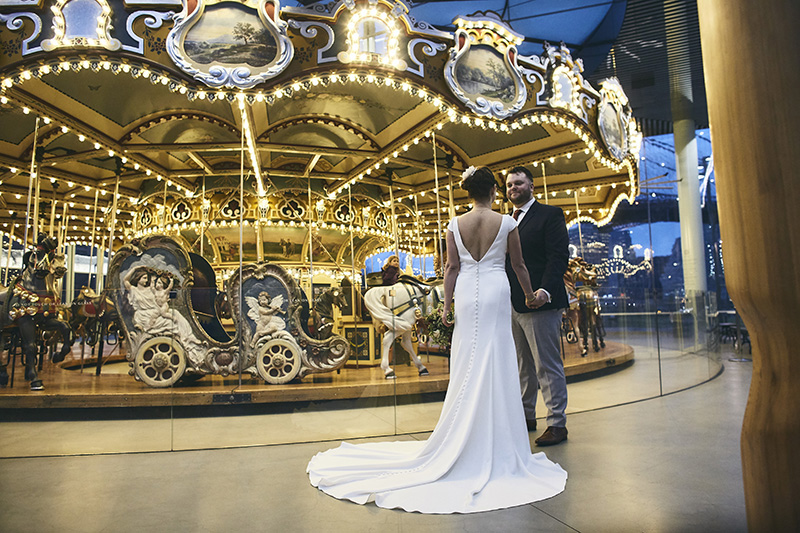 Bride and groom posing by the carousel in NYC