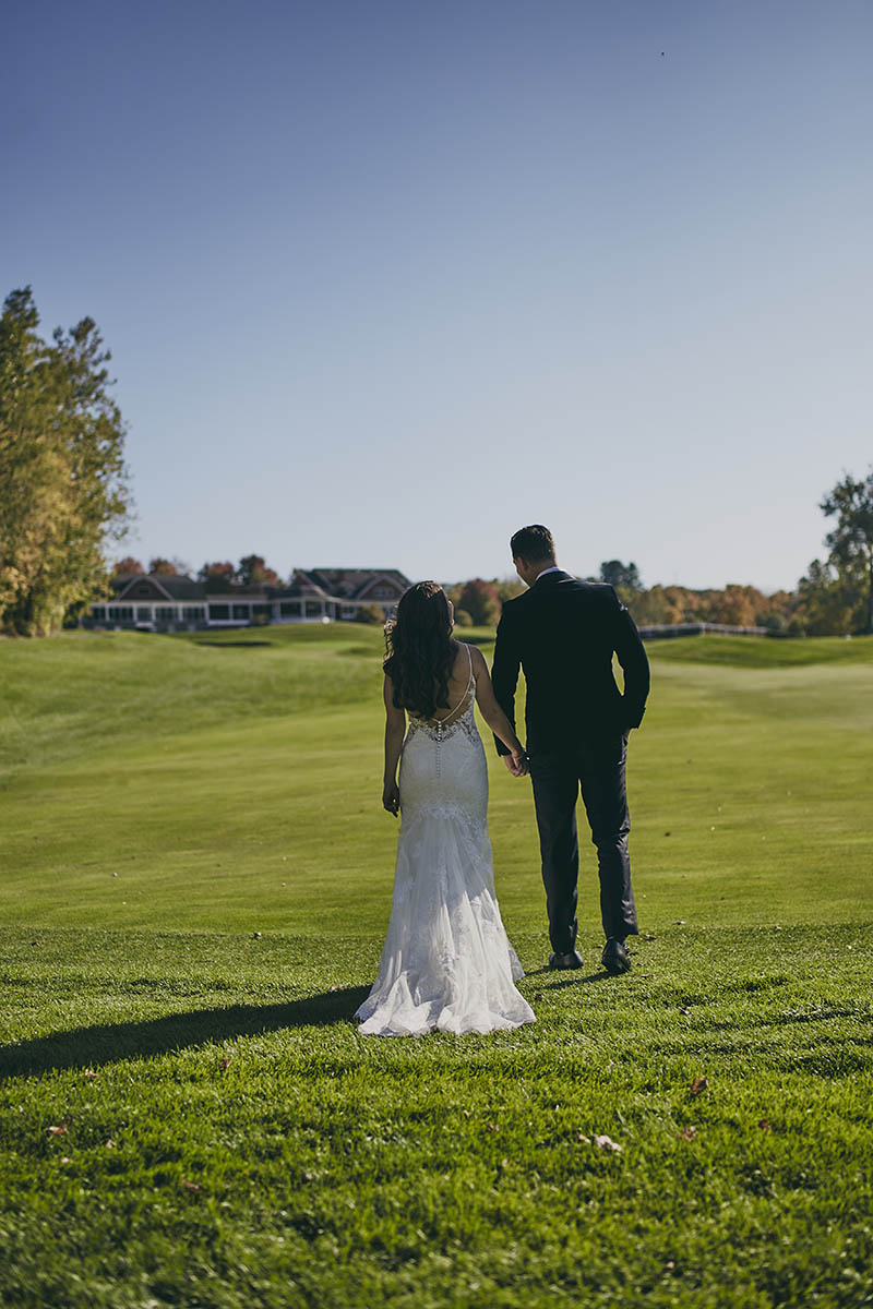 Bride and groom walking away on golf course