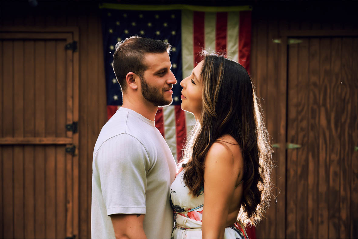 Couple facing each other with American flag in the background