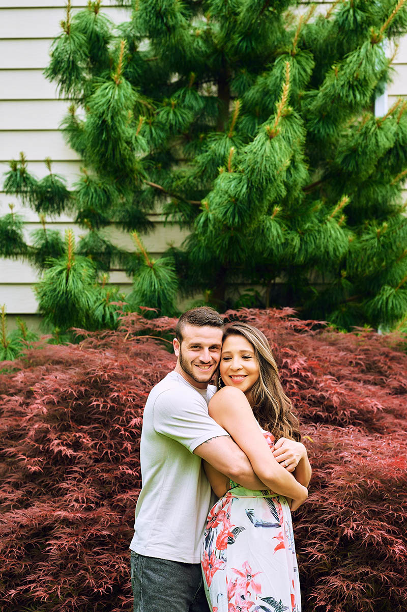 Engagement couple hugging each other in front of their home