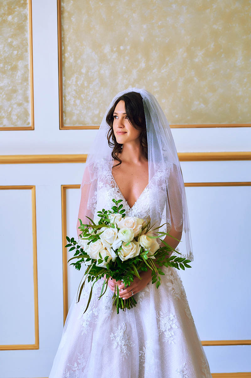 Bride holding flowers and looking out the window