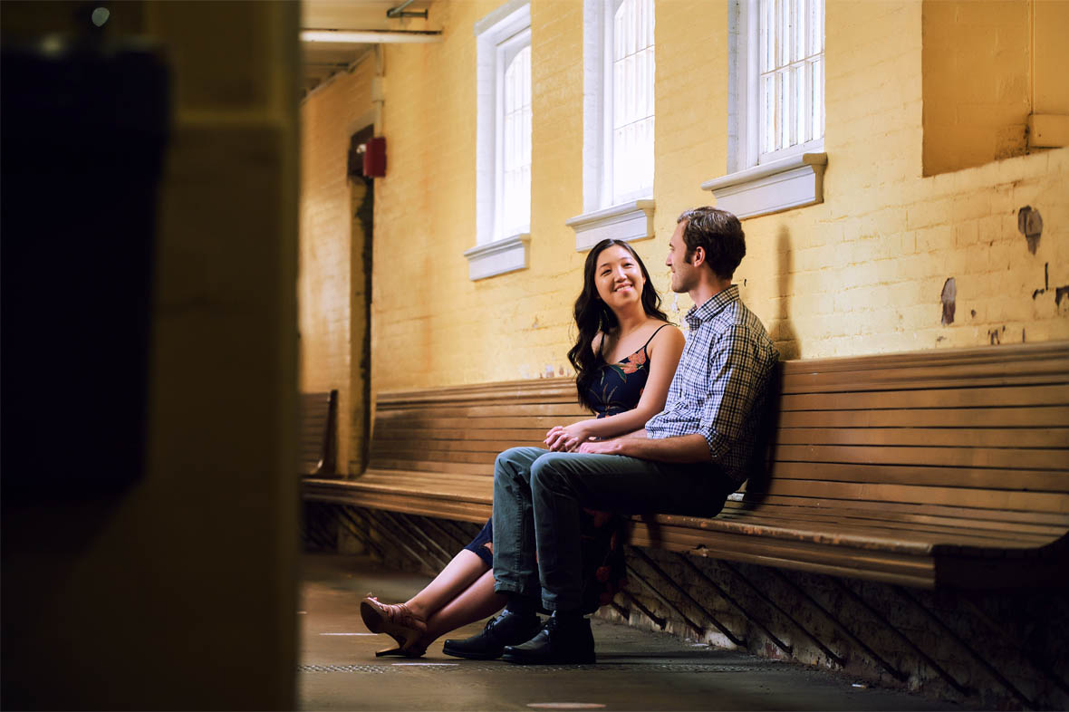 Couple sitting on bench inside of abondoned building
