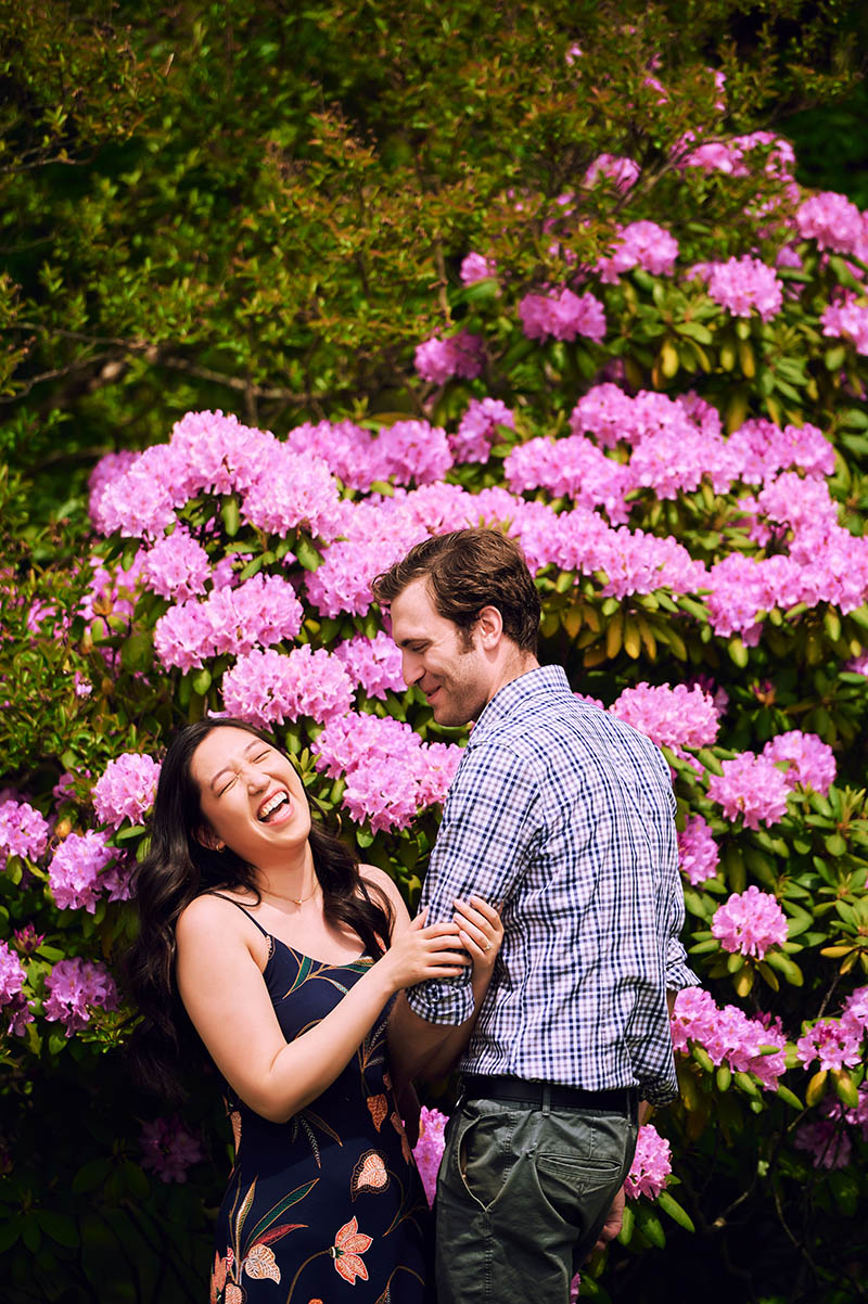 Couple laughing in front of pink flowers