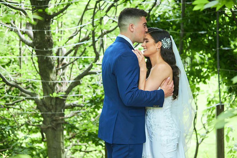 Groom kissing bride in forehead