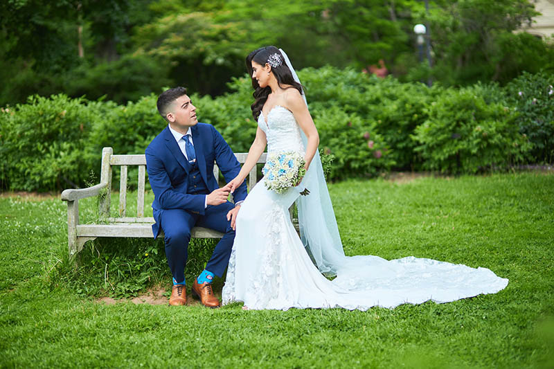 Groom sitting on bench and holding brides hand