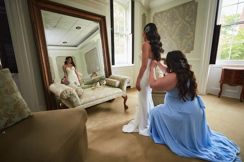 Maid of honor helping bride put the dress on