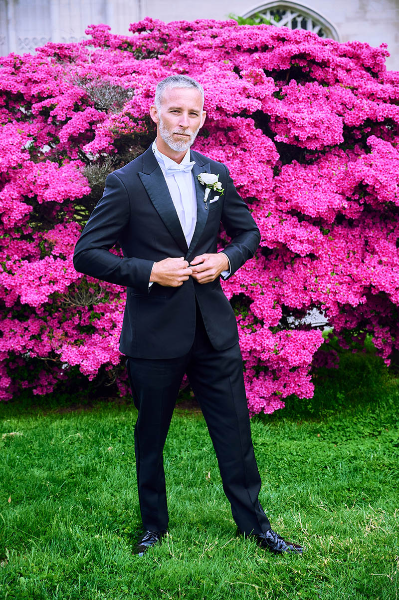 Groom portrait in front of pink flowers