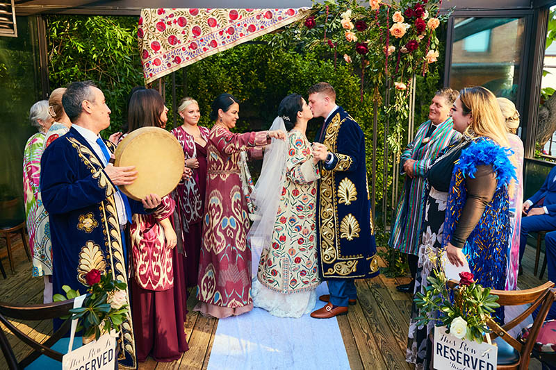 Bride and groom in Uzbek traditional attire kissing