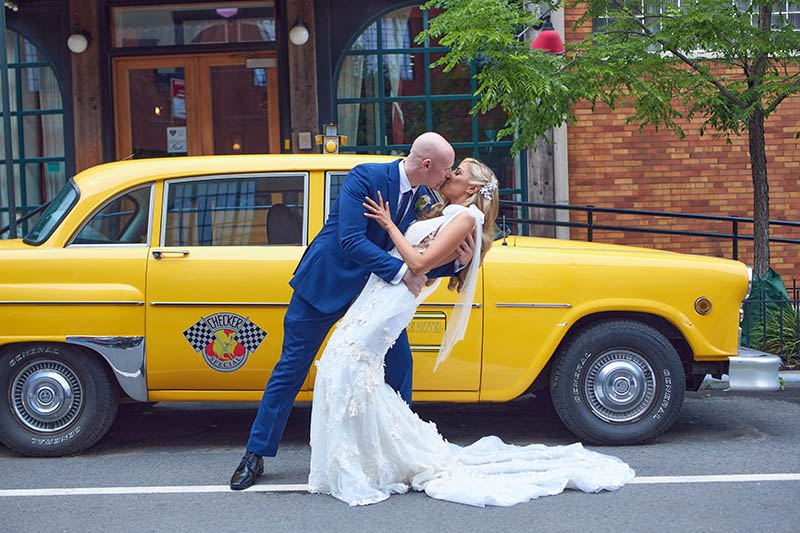 Groom kissing bride in front of the checkers cab