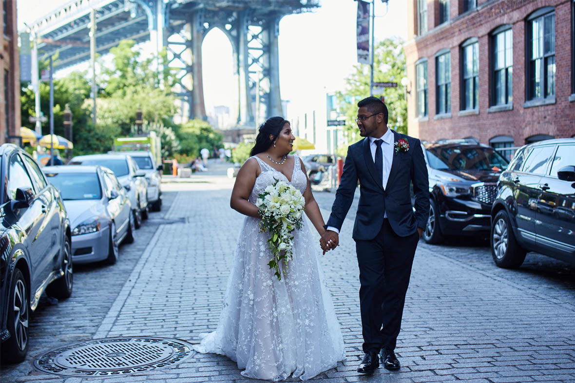 Bride and groom holding hands and walking in DUMBO