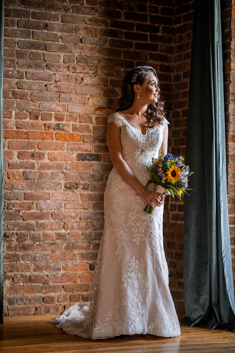 Bride holding flowers and looking out the window