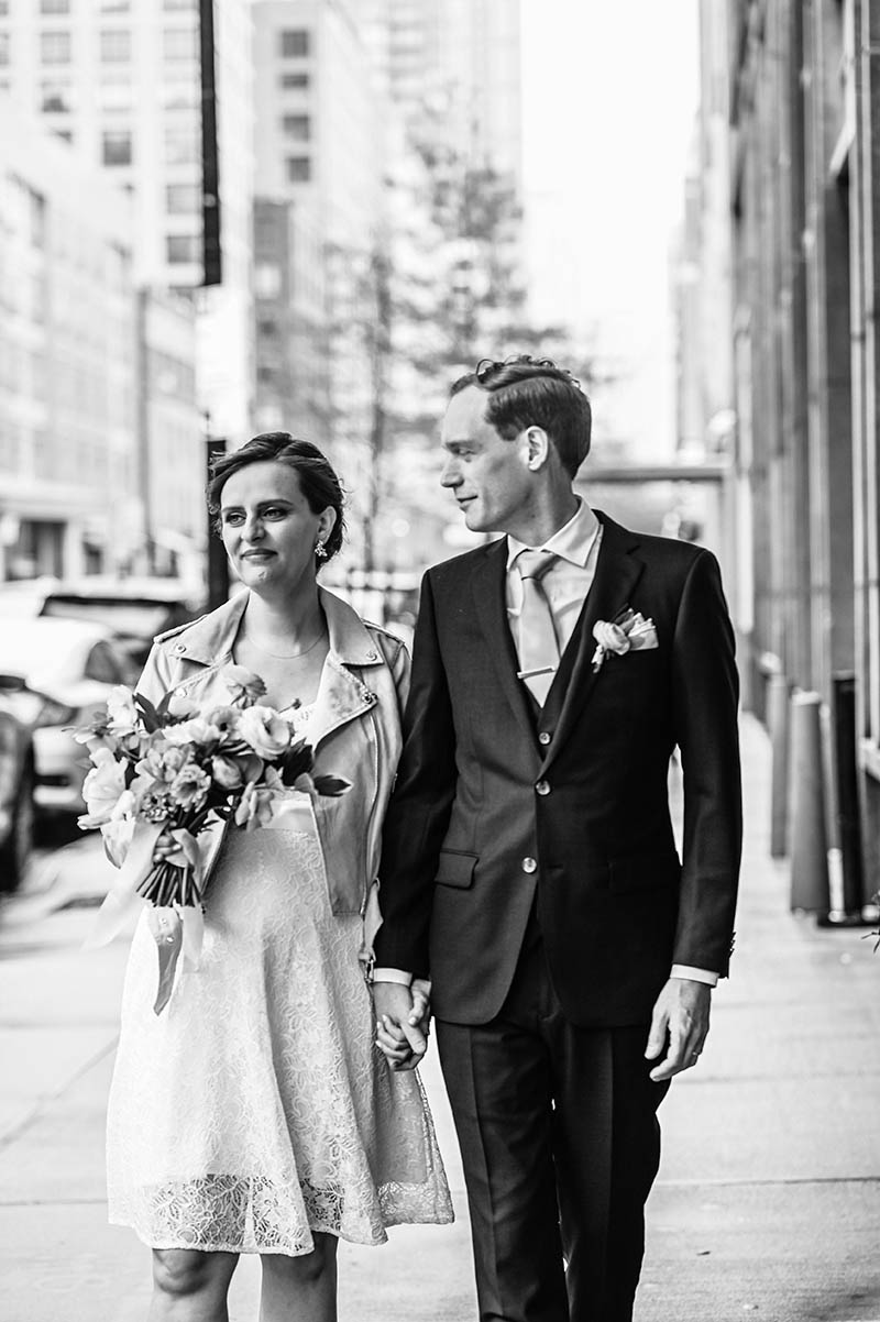Black and white photo of bride and groom walking outside