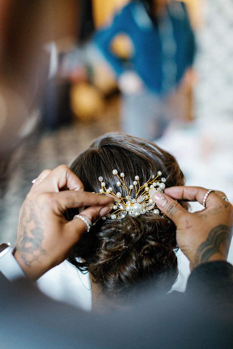 Hair stylist putting hair piece in brides hair