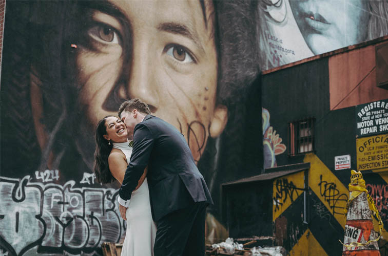 Groom kissing bride in front of billboard