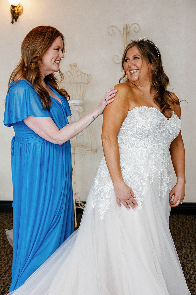 Bridesmaid helping bride get into the dress