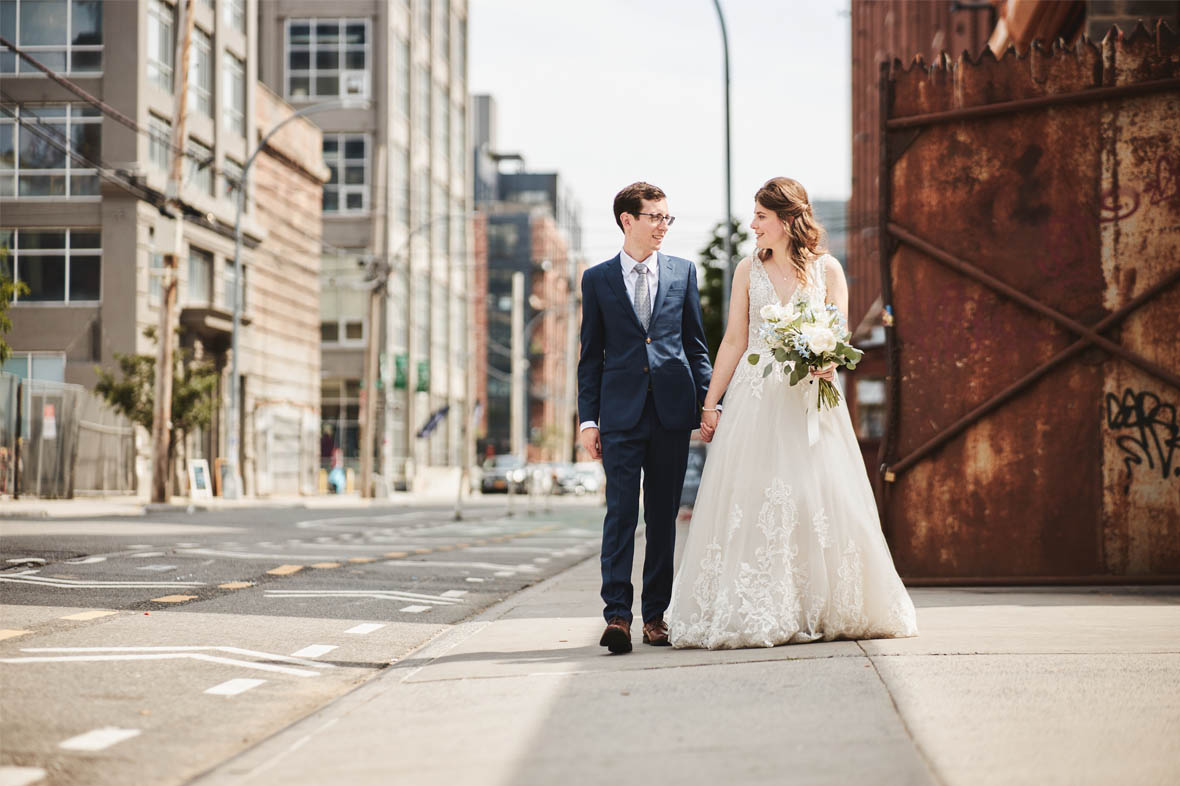 Bride and groom walking on sidewalk