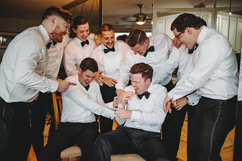 Groomsmen laughing and hitting groom
