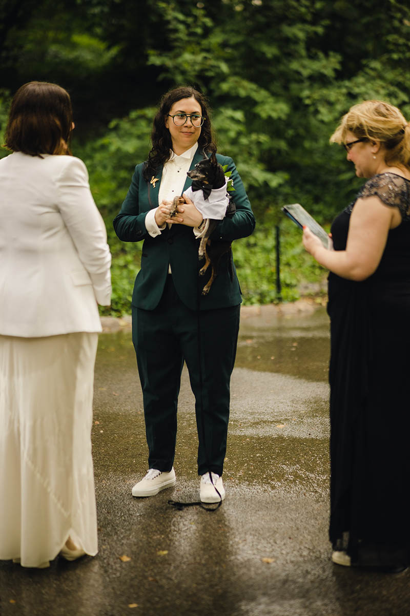 Bride holding dog during wedding ceremony