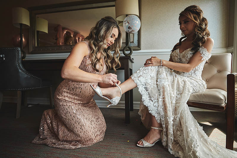 Maid of honor helping bride put the shoes on