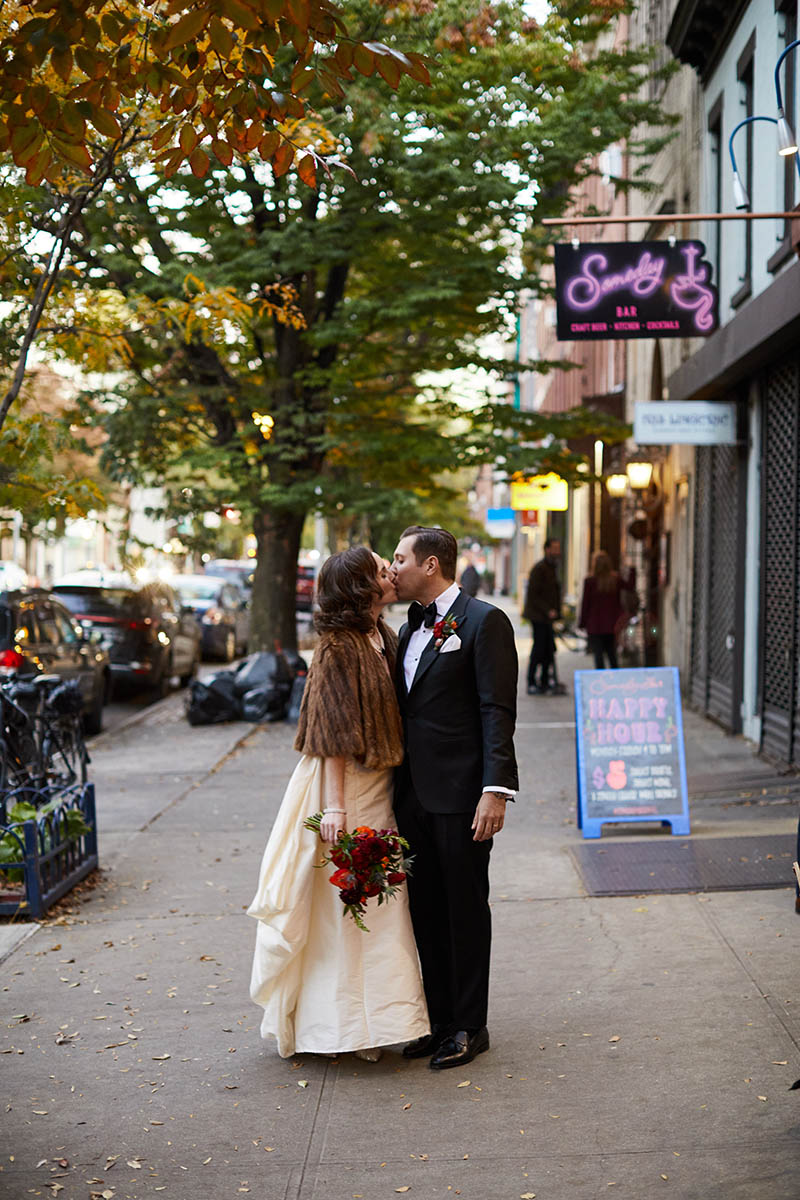 Bride and groom kissing on sidewalk