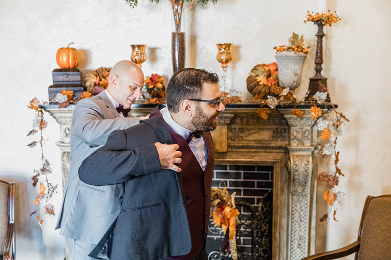 Best man helping groom put the suit on