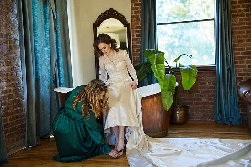 Bridesmaid helping bride put the shoes on