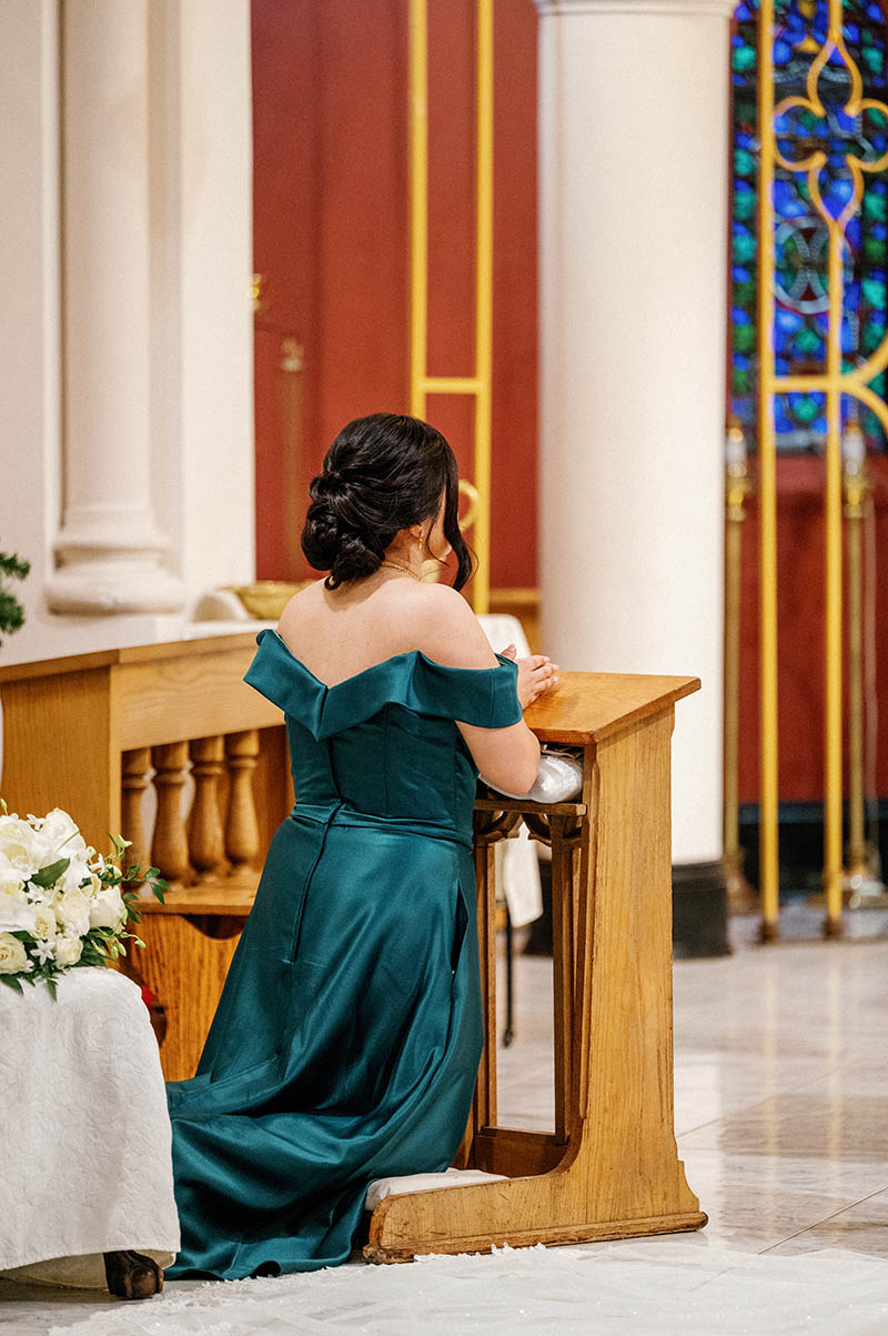 Maid of honor kneeling during church wedding ceremony