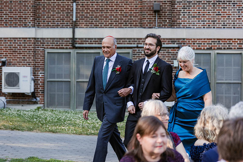 Groom walking down the aisle with parents