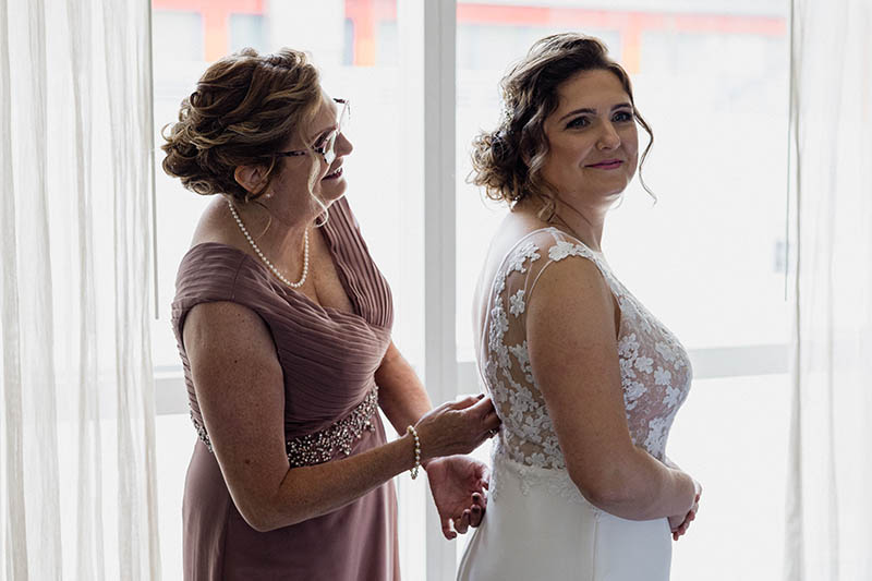 Mother helping bride put the wedding dress on