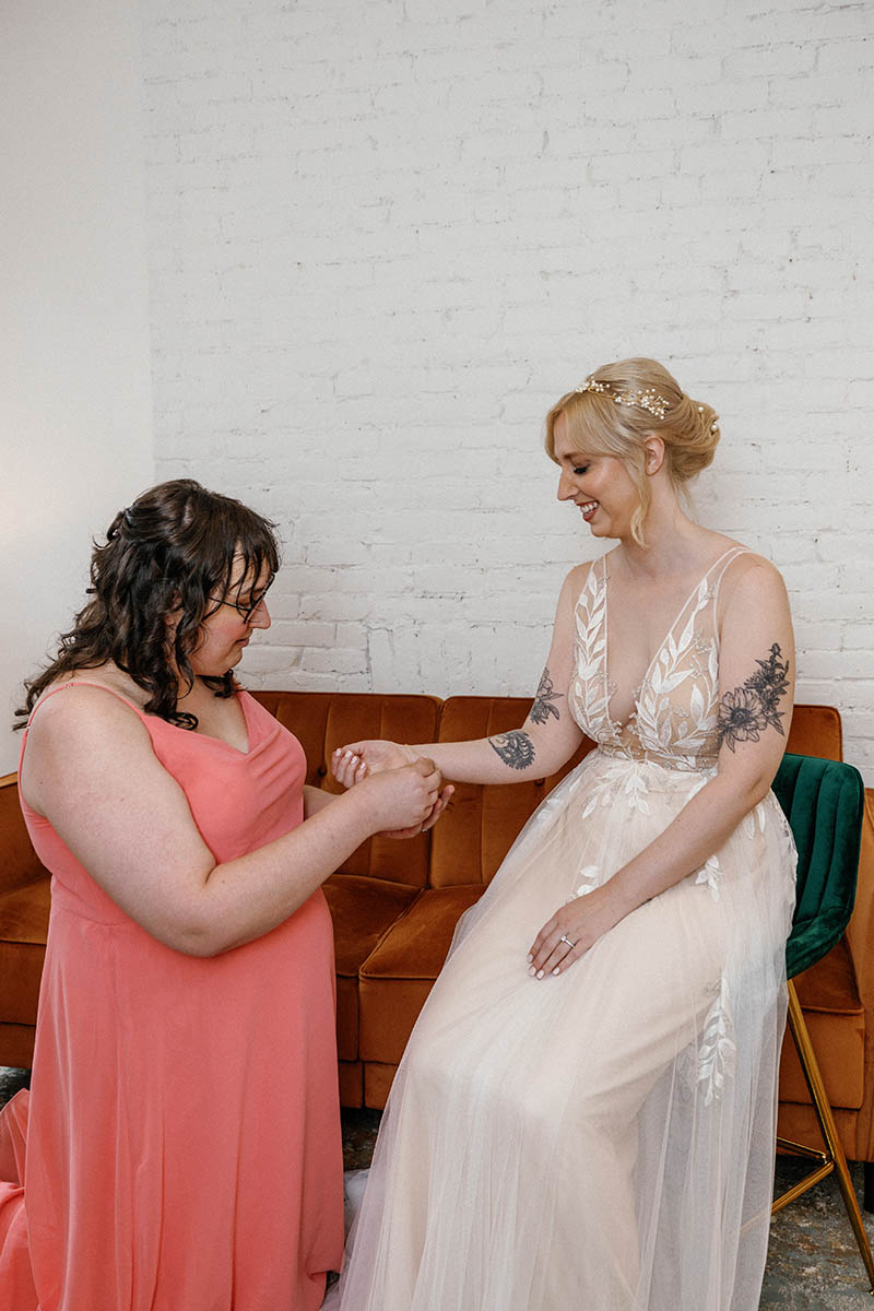 Bridesmaid helping bride put the jewelry on